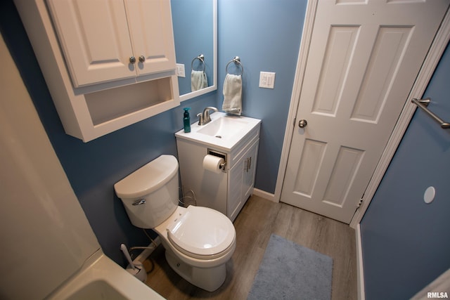 bathroom featuring toilet, vanity, baseboards, and wood finished floors