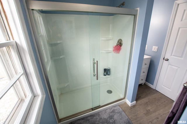 full bathroom featuring a stall shower, vanity, baseboards, and wood finished floors