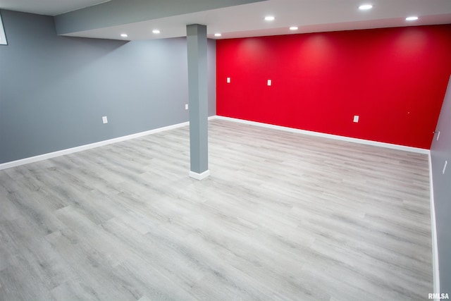 finished below grade area featuring baseboards, wood finished floors, and an accent wall