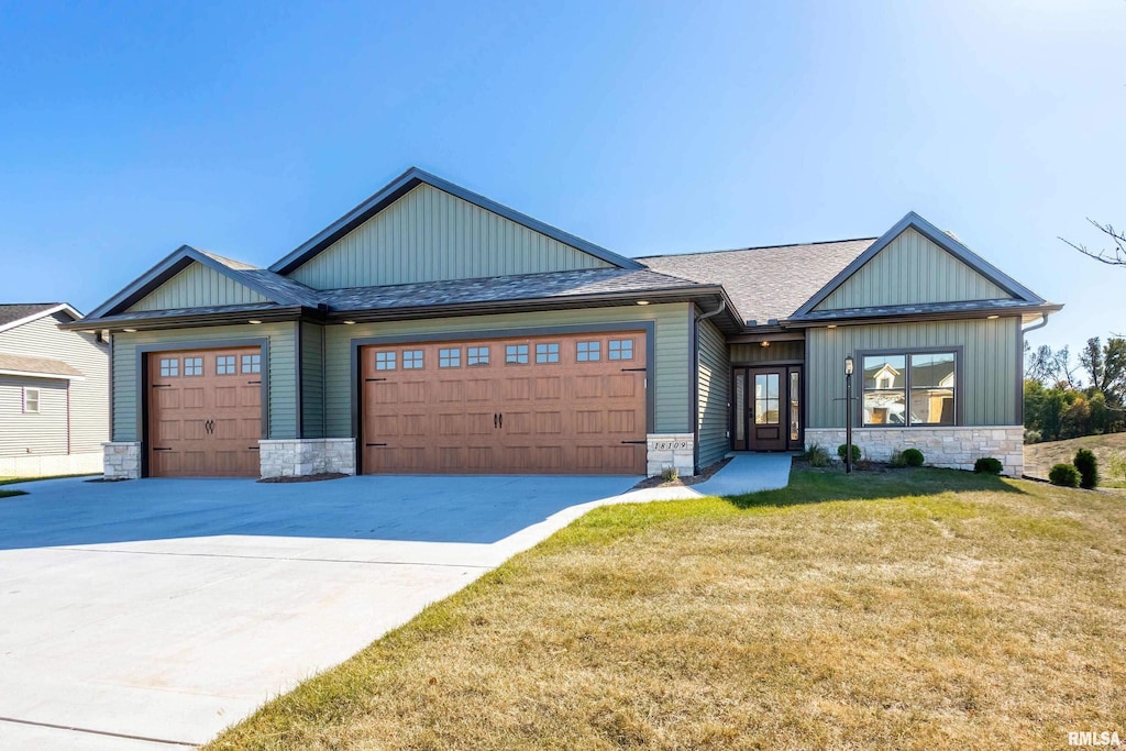 craftsman inspired home with a shingled roof, an attached garage, a front yard, stone siding, and driveway