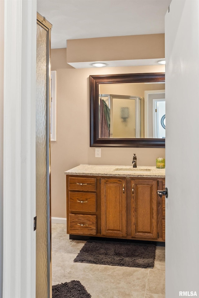 bathroom featuring tile patterned flooring, vanity, and a shower with shower door