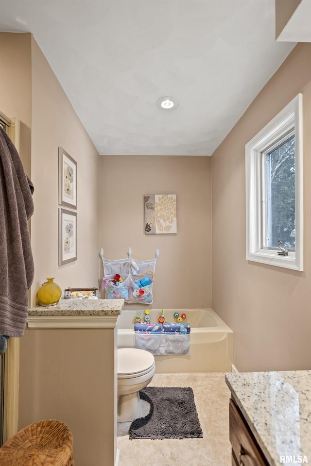 bathroom featuring tile patterned floors, vanity, toilet, and a bathing tub