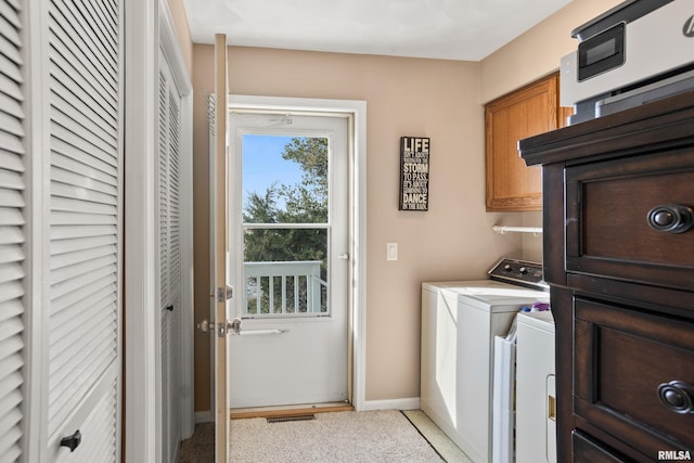 clothes washing area featuring washer and dryer and cabinets