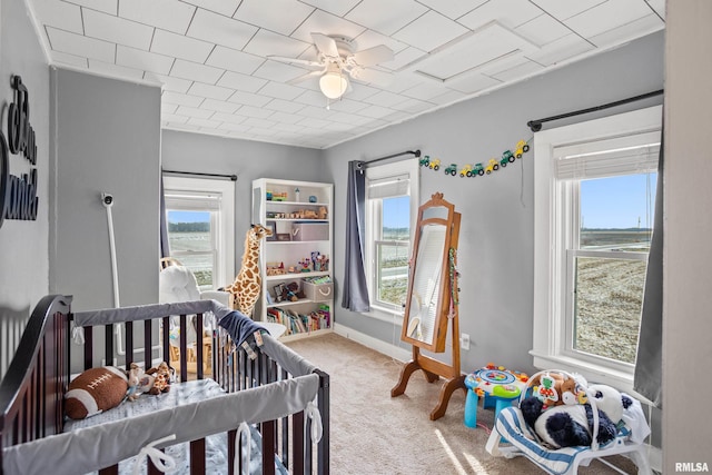 carpeted bedroom with ceiling fan, a water view, and a nursery area