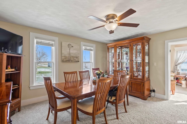 dining space with ceiling fan, a textured ceiling, a wealth of natural light, and light carpet