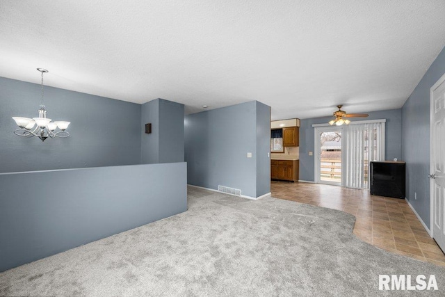 unfurnished living room with ceiling fan with notable chandelier, light colored carpet, and a textured ceiling