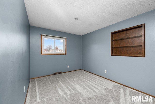 carpeted empty room with a textured ceiling