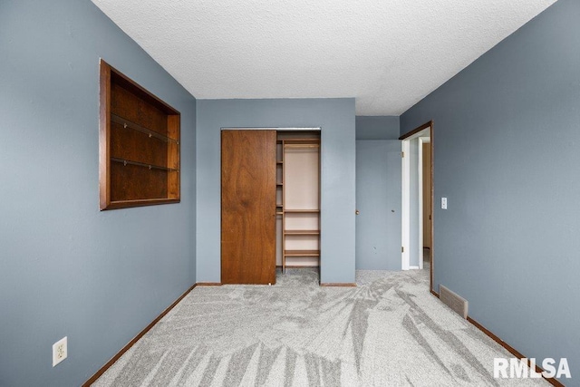 unfurnished bedroom featuring a textured ceiling, light colored carpet, and a closet