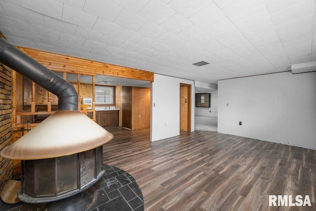 interior space with wooden walls, a wood stove, and dark wood-type flooring