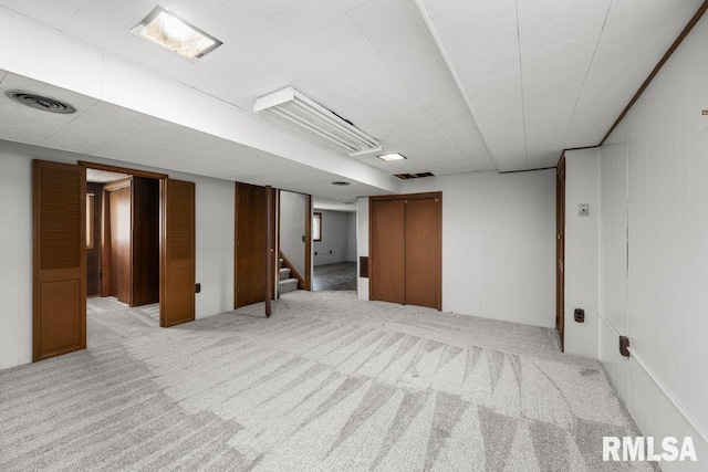 basement with light colored carpet and wooden walls