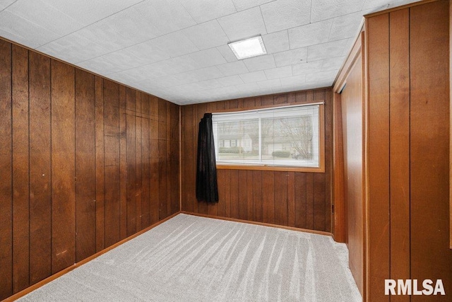 carpeted spare room with wooden walls