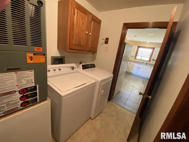 laundry room with cabinets, washing machine and clothes dryer, sink, light tile patterned floors, and heating unit