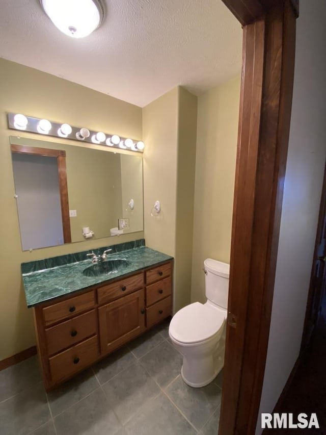 bathroom with tile patterned floors, vanity, toilet, and a textured ceiling