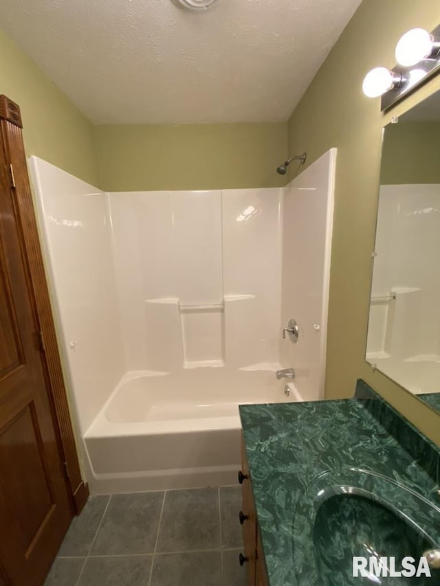 bathroom featuring tile patterned floors, vanity, a textured ceiling, and washtub / shower combination