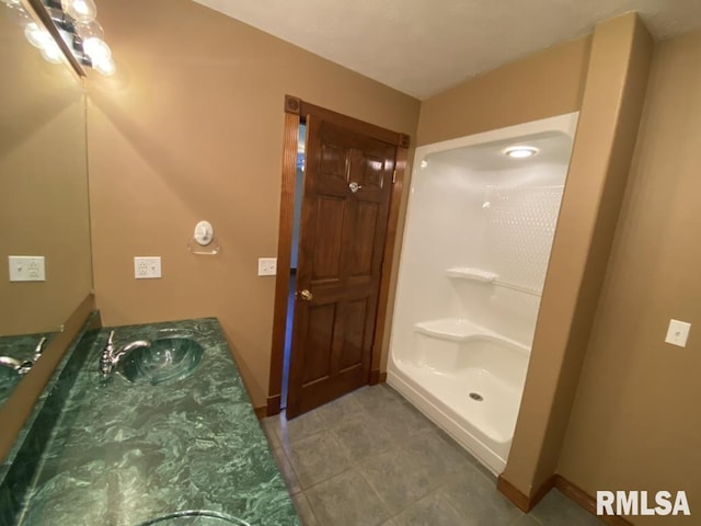 bathroom featuring tile patterned flooring, a shower, and vanity