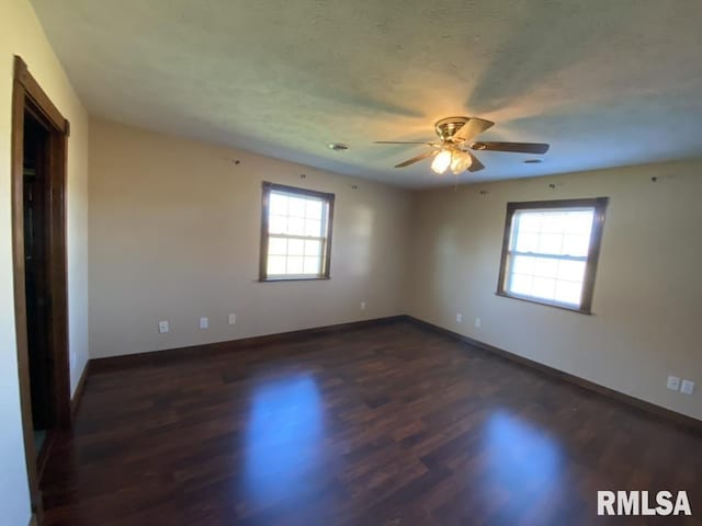 spare room with a wealth of natural light, ceiling fan, and dark hardwood / wood-style floors