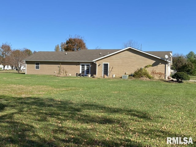 rear view of property with central AC and a yard