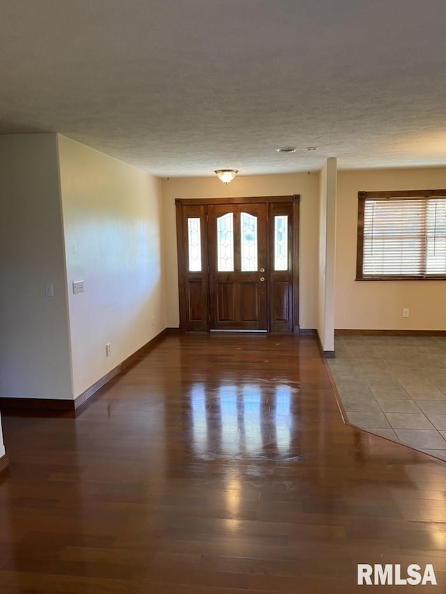 entrance foyer with a textured ceiling, a wealth of natural light, and dark wood-type flooring