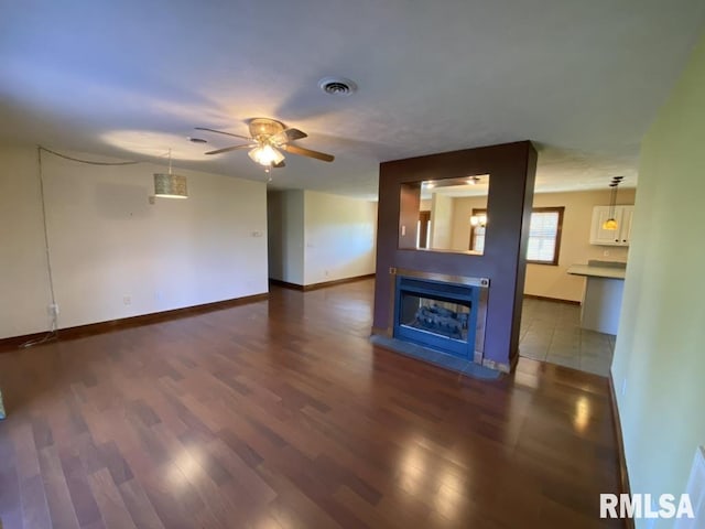 unfurnished living room with ceiling fan, a fireplace, and dark hardwood / wood-style floors