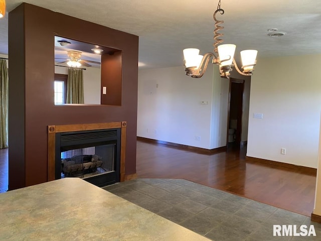 unfurnished dining area featuring ceiling fan with notable chandelier and dark hardwood / wood-style floors