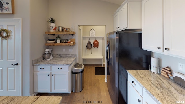 kitchen featuring stainless steel fridge, light hardwood / wood-style flooring, white cabinets, and light stone counters