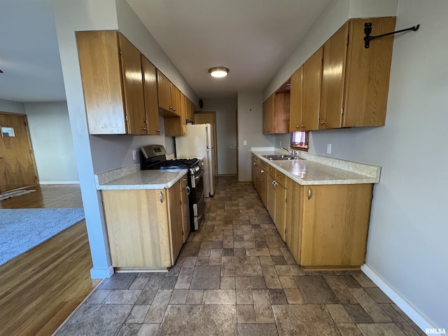 kitchen featuring dark hardwood / wood-style flooring, stainless steel gas stove, white fridge, and sink