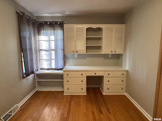 unfurnished office featuring light hardwood / wood-style flooring and built in desk