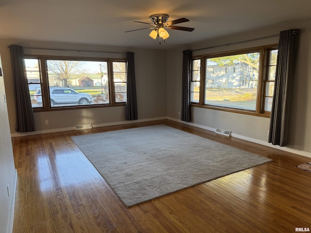 empty room with hardwood / wood-style floors, a wealth of natural light, and ceiling fan