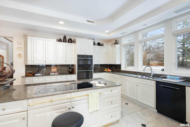 kitchen featuring tasteful backsplash, sink, black appliances, dark stone countertops, and white cabinets