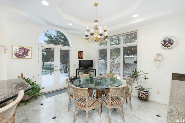 dining space with plenty of natural light, a raised ceiling, a chandelier, and french doors