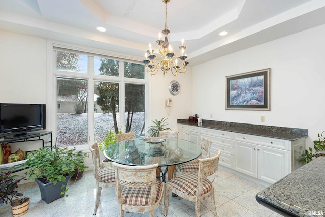 dining space with a raised ceiling and a chandelier