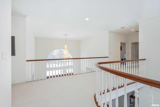 hall with carpet, ornamental molding, and a notable chandelier