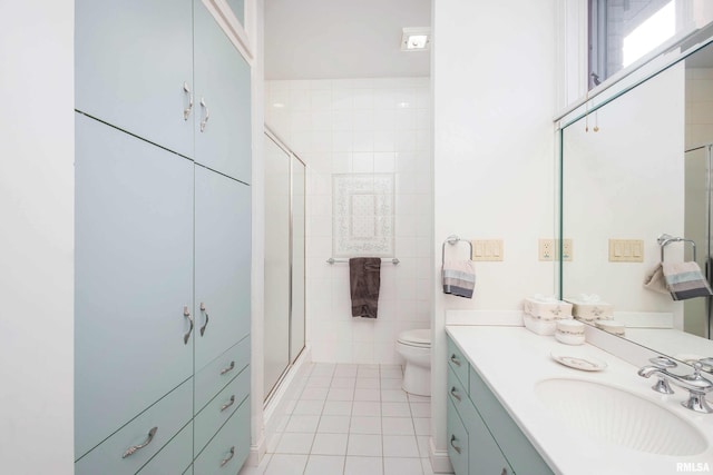 bathroom featuring tile patterned floors, vanity, a shower with door, tile walls, and toilet