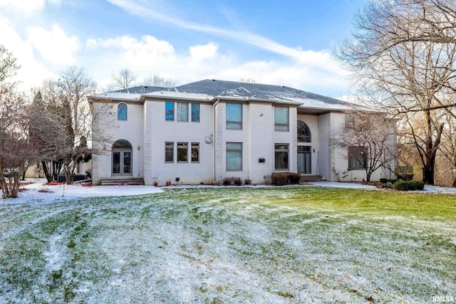 snow covered back of property with a yard and french doors