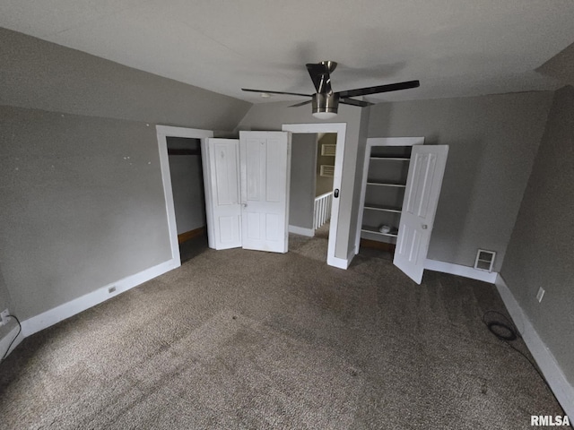 unfurnished bedroom featuring dark colored carpet, lofted ceiling, visible vents, a ceiling fan, and baseboards