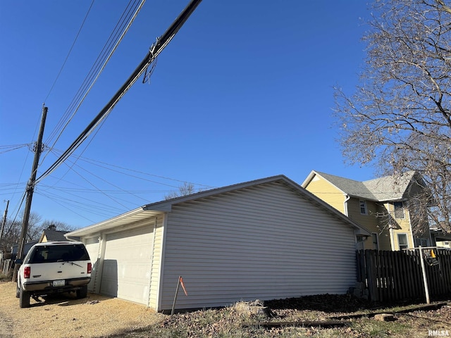 view of side of home with fence and an outbuilding