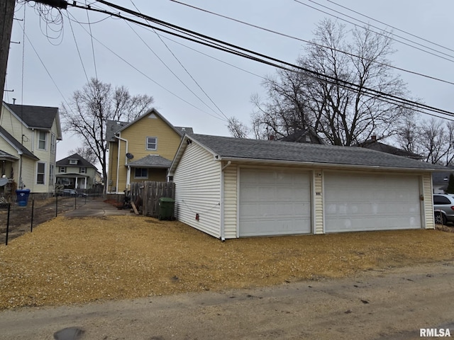 exterior space with an outbuilding, a detached garage, and fence