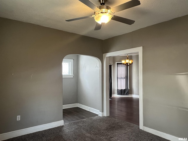 empty room with arched walkways, carpet floors, a textured ceiling, and baseboards