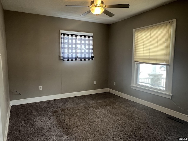 spare room featuring a ceiling fan, dark colored carpet, visible vents, and baseboards