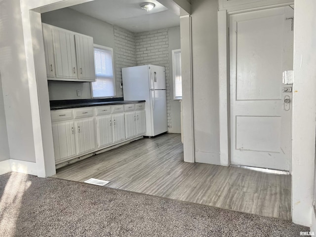 kitchen with white cabinetry, white refrigerator, and light wood-type flooring