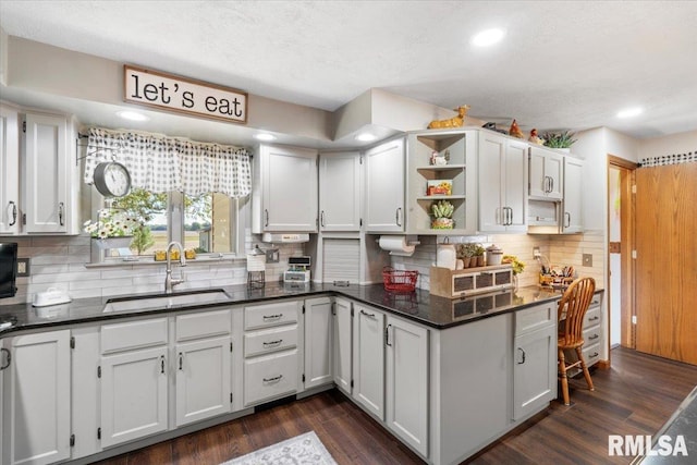 kitchen with white cabinetry, sink, dark wood-type flooring, backsplash, and a textured ceiling