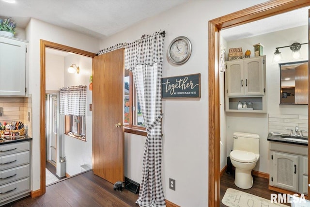 bathroom with decorative backsplash, wood-type flooring, vanity, and toilet