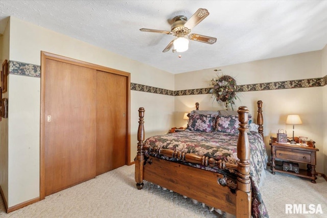 carpeted bedroom with ceiling fan, a closet, and a textured ceiling