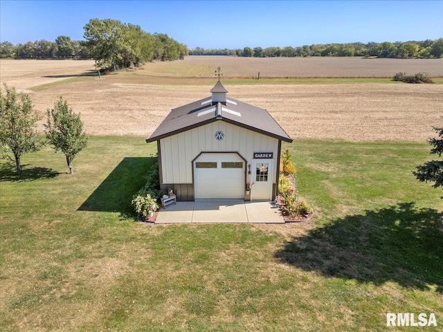 view of outdoor structure with a lawn, a rural view, and a garage