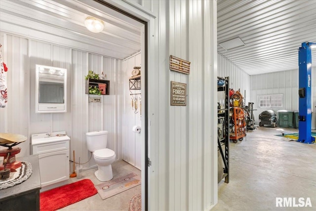 bathroom with wooden walls, concrete floors, and toilet