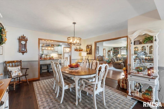 dining room with dark hardwood / wood-style floors and an inviting chandelier