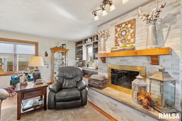 sitting room with hardwood / wood-style flooring, brick wall, a textured ceiling, and a brick fireplace