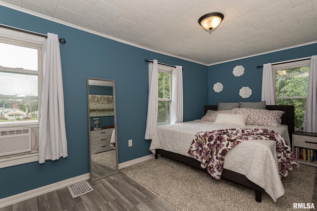 bedroom featuring multiple windows, hardwood / wood-style floors, cooling unit, and ornamental molding