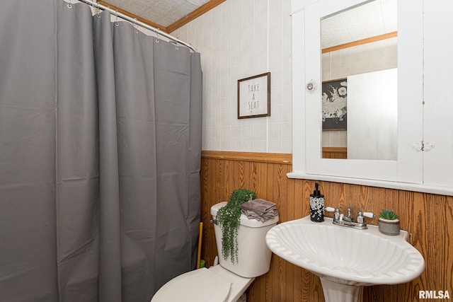 bathroom with sink, a shower with curtain, toilet, wooden walls, and tile walls