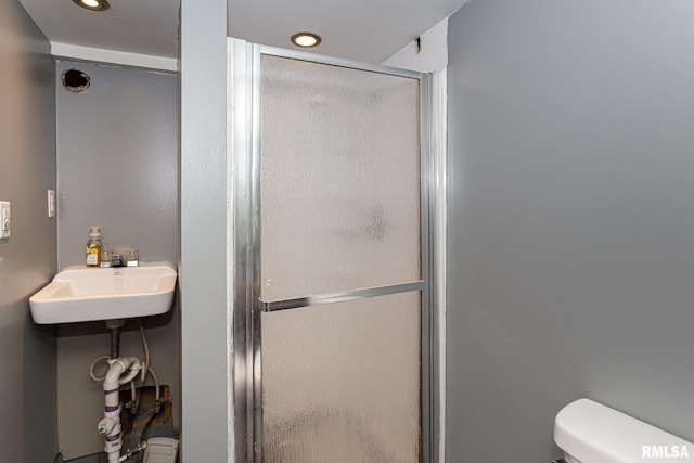 bathroom with an enclosed shower, toilet, and sink